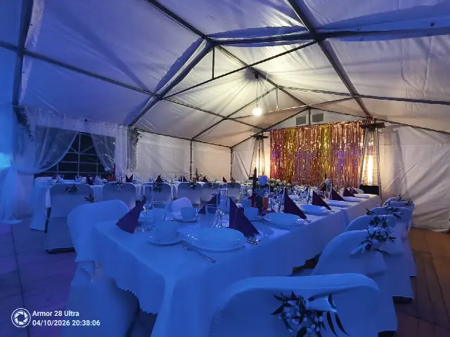 Wnętrze namiotu ze stołami w białych obrusach i niebieskim oświetleniem