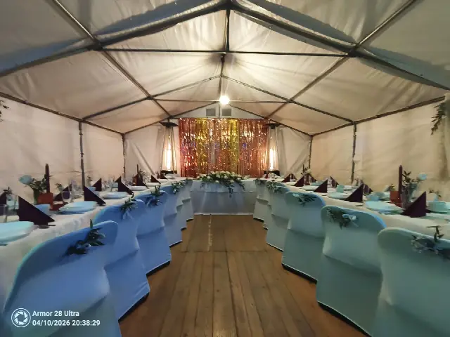 Stoły z białymi obrusami i krzesła w pokrowcach w udekorowanym namiocie