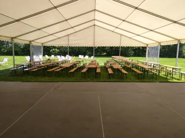 Widok spod dachu hali na parkiet oraz ustawione dalej stoły i ławki